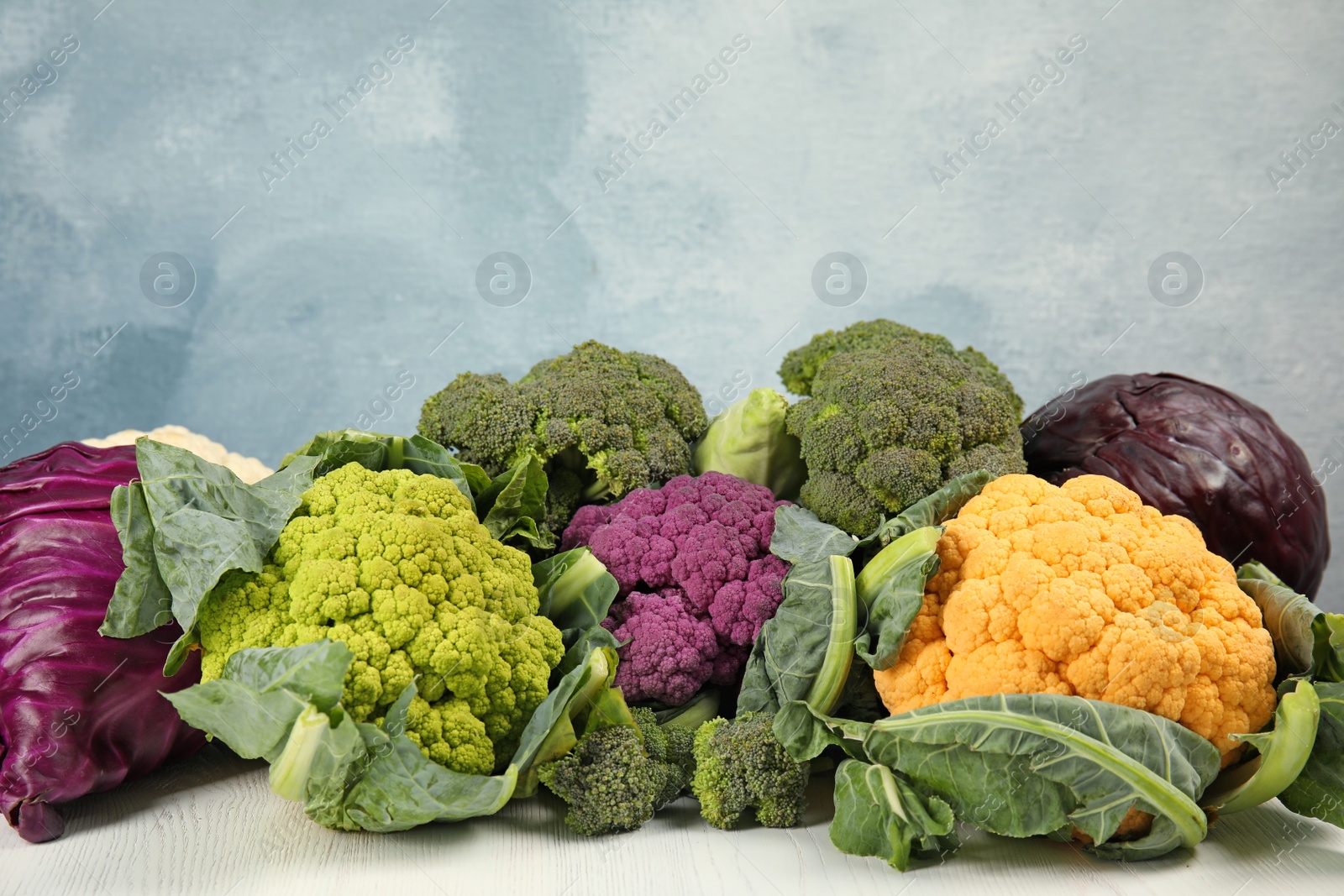 Photo of Different cabbages on wooden table. Healthy food