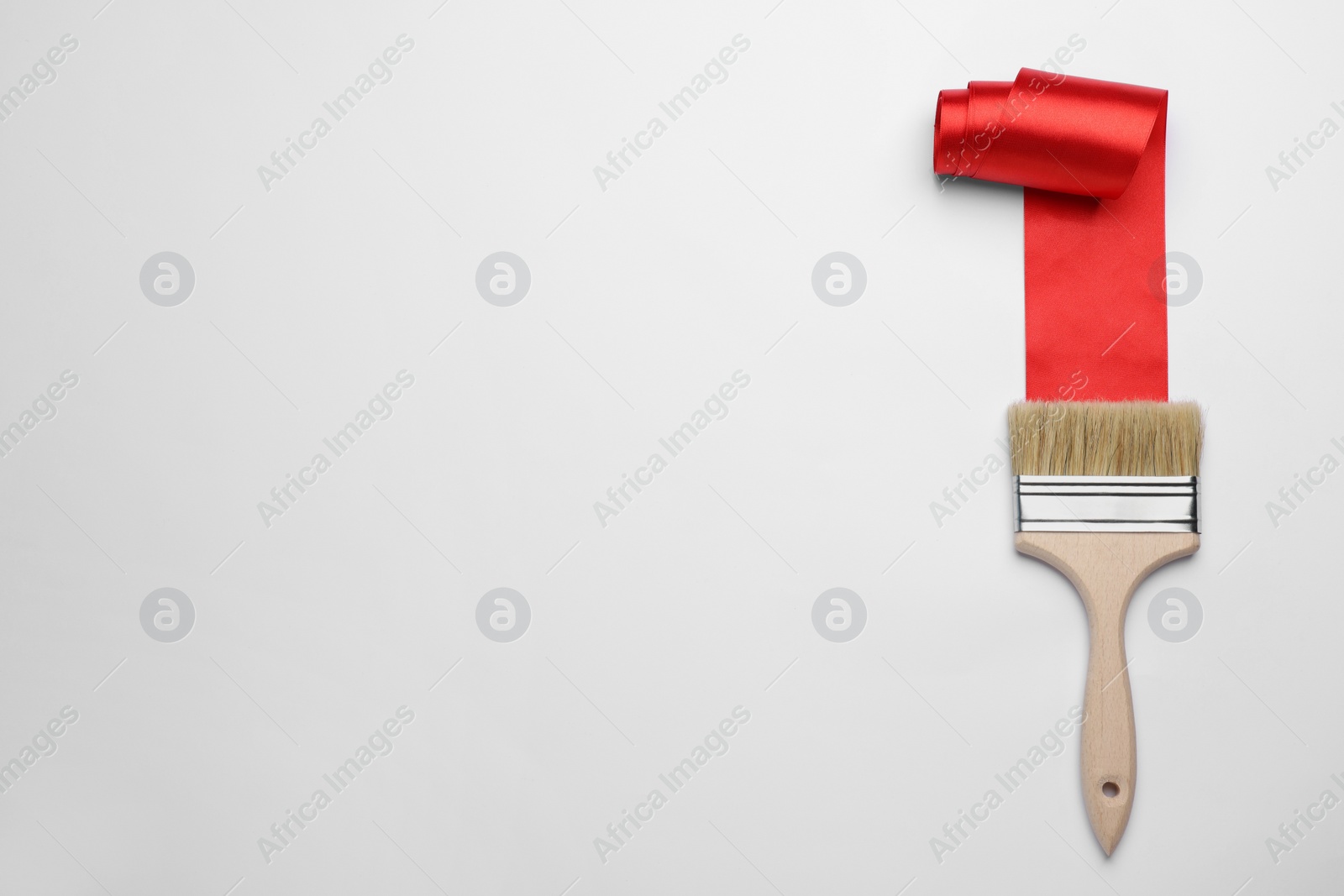 Photo of Brush painting with red ribbon on light background, top view. Space for text. Creative concept