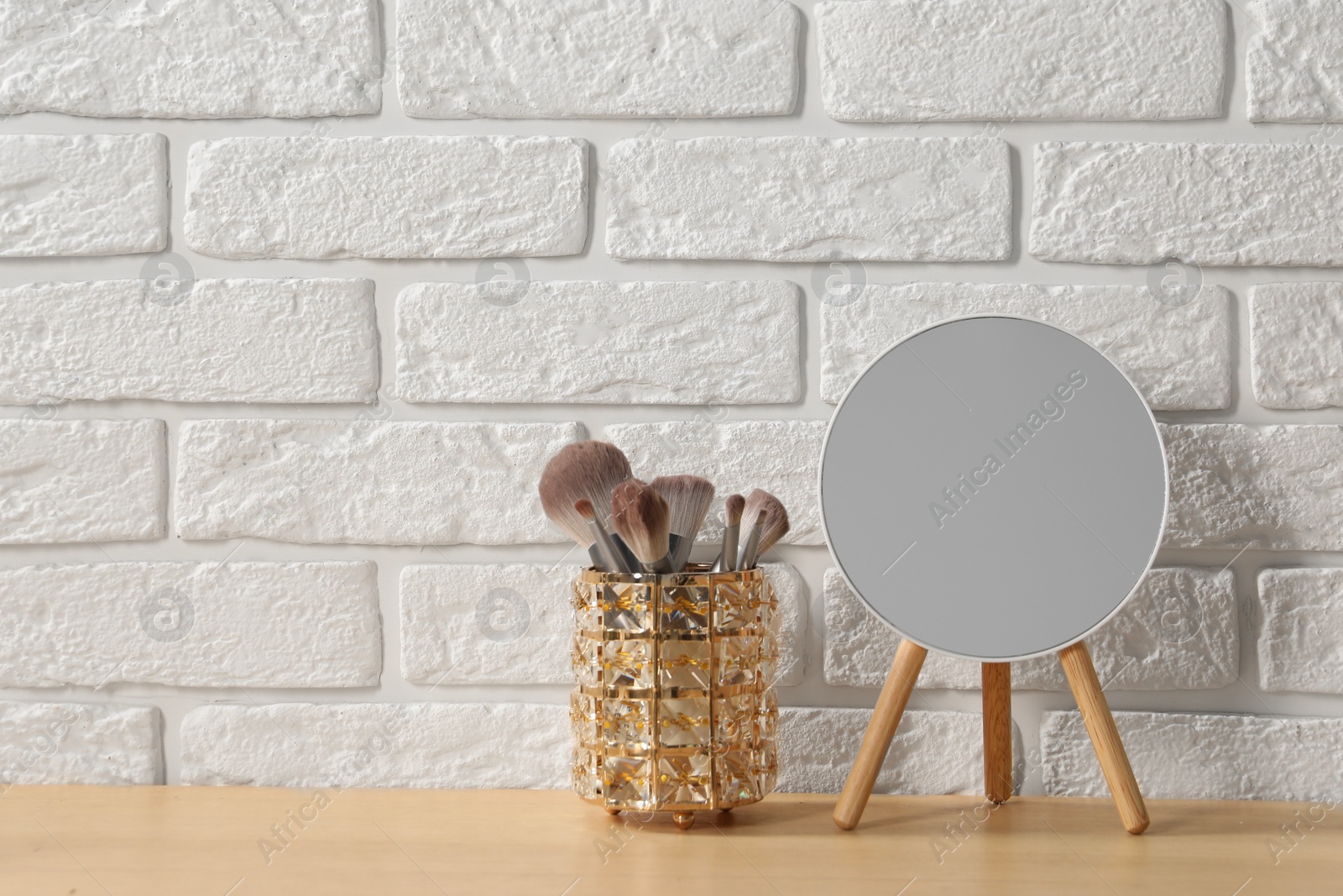 Photo of Mirror and makeup brushes on wooden dressing table in room. Space for text