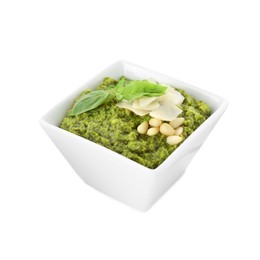 Photo of Bowl with delicious pesto sauce, cheese, pine nuts and basil leaves isolated on white