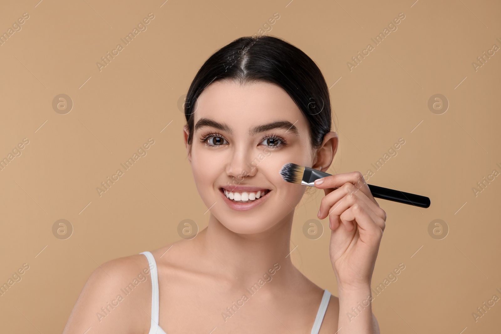 Photo of Teenage girl with makeup brush on beige background