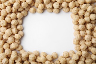 Photo of Frame made of tasty cereal balls on white background, top view. Space for text