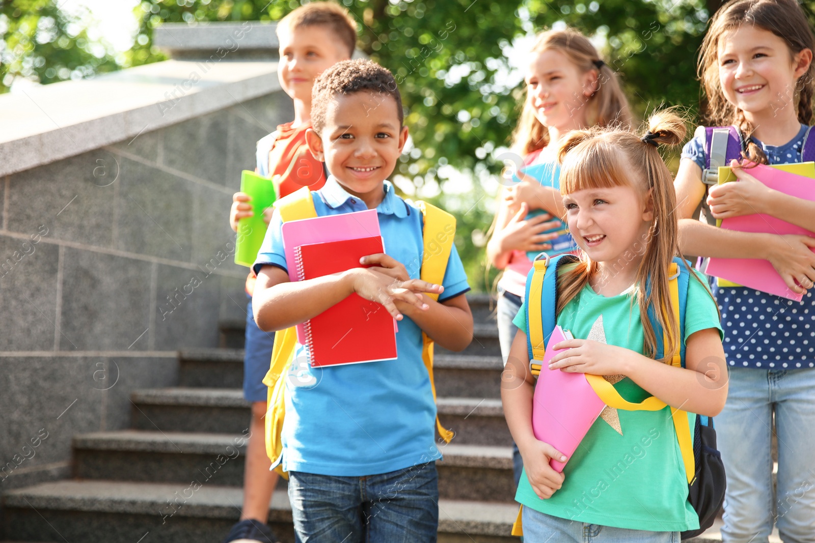 Photo of Cute little children with backpacks and notebooks outdoors. Elementary school