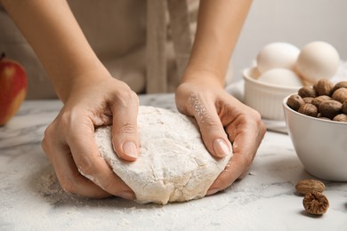 Woman kneading dough at white marble table, closeup