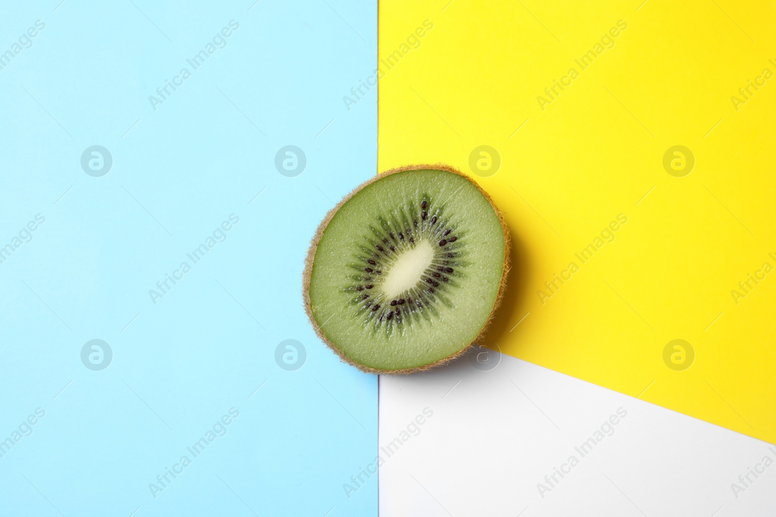 Photo of Half of fresh kiwi on color background, top view