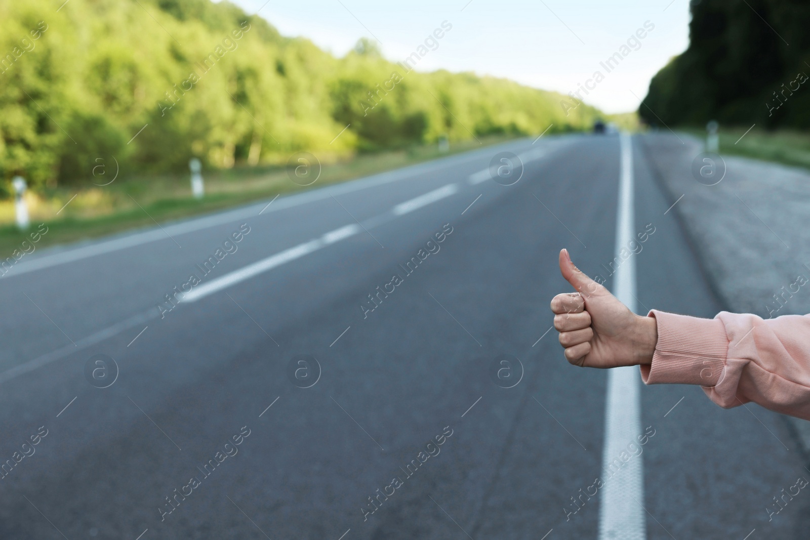 Photo of Woman catching car on road, closeup. Hitchhiking trip