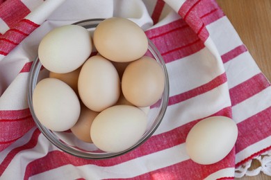 Fresh raw eggs and towel on table, flat lay