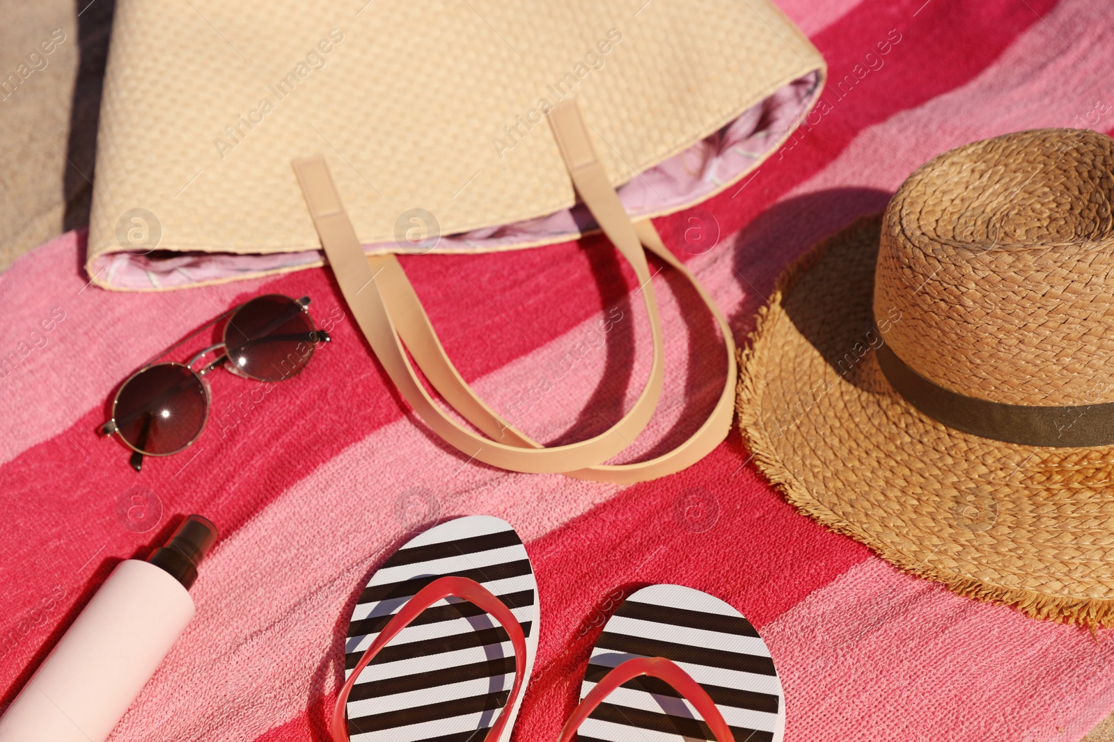 Photo of Straw hat, bag and other beach items on striped towel, closeup. View from above