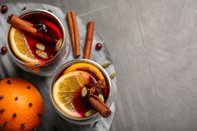 Photo of Board with glasses of tasty mulled wine on grey table, top view. Space for text