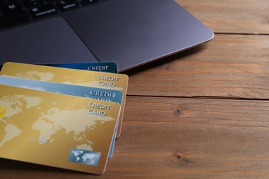 Photo of Credit cards and laptop on wooden table, space for text