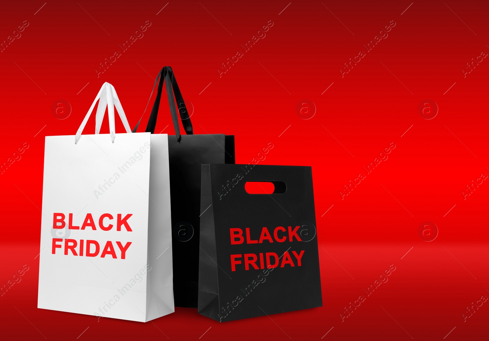 Image of Paper shopping bags on red background, space for text. Black friday