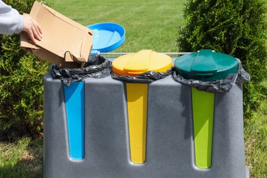Photo of Woman throwing cardboard in bin outdoors, closeup. Recycling concept