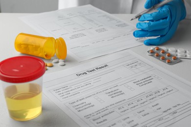 Photo of Laboratory worker filling drug test result form at table, closeup