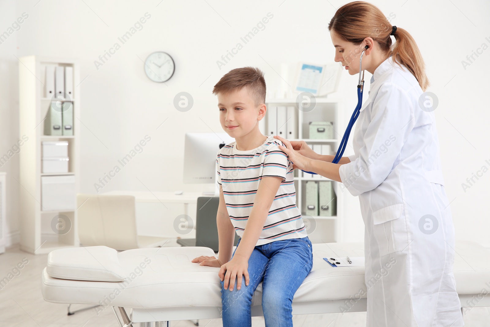 Photo of Children's doctor examining patient with stethoscope in hospital