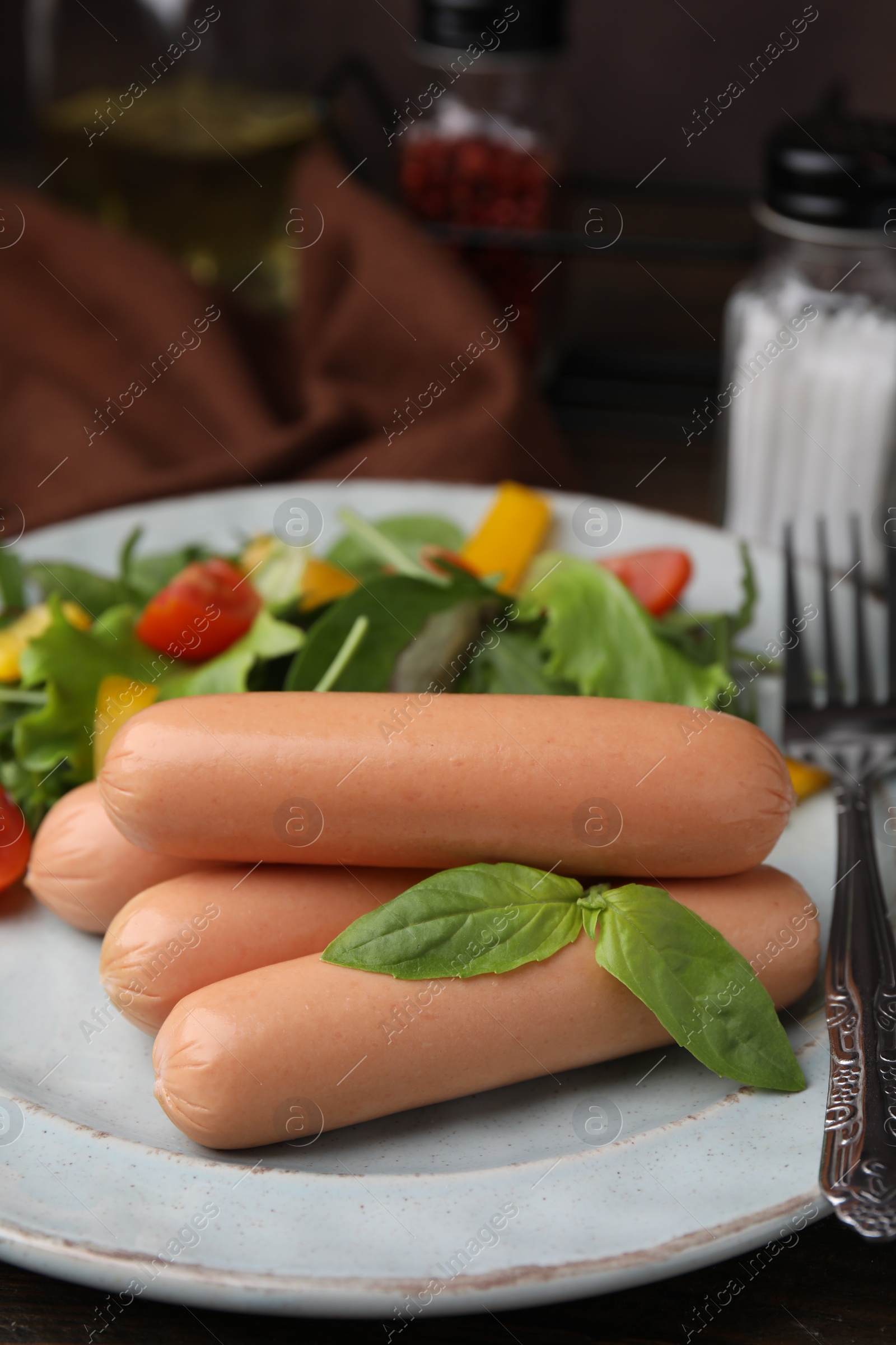 Photo of Delicious boiled sausages with salad on table, closeup