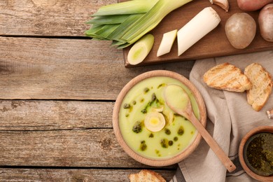 Photo of Delicious leek soup on wooden table, flat lay. Space for text
