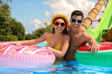 Photo of Happy couple with inflatable rings in swimming pool. Summer vacation