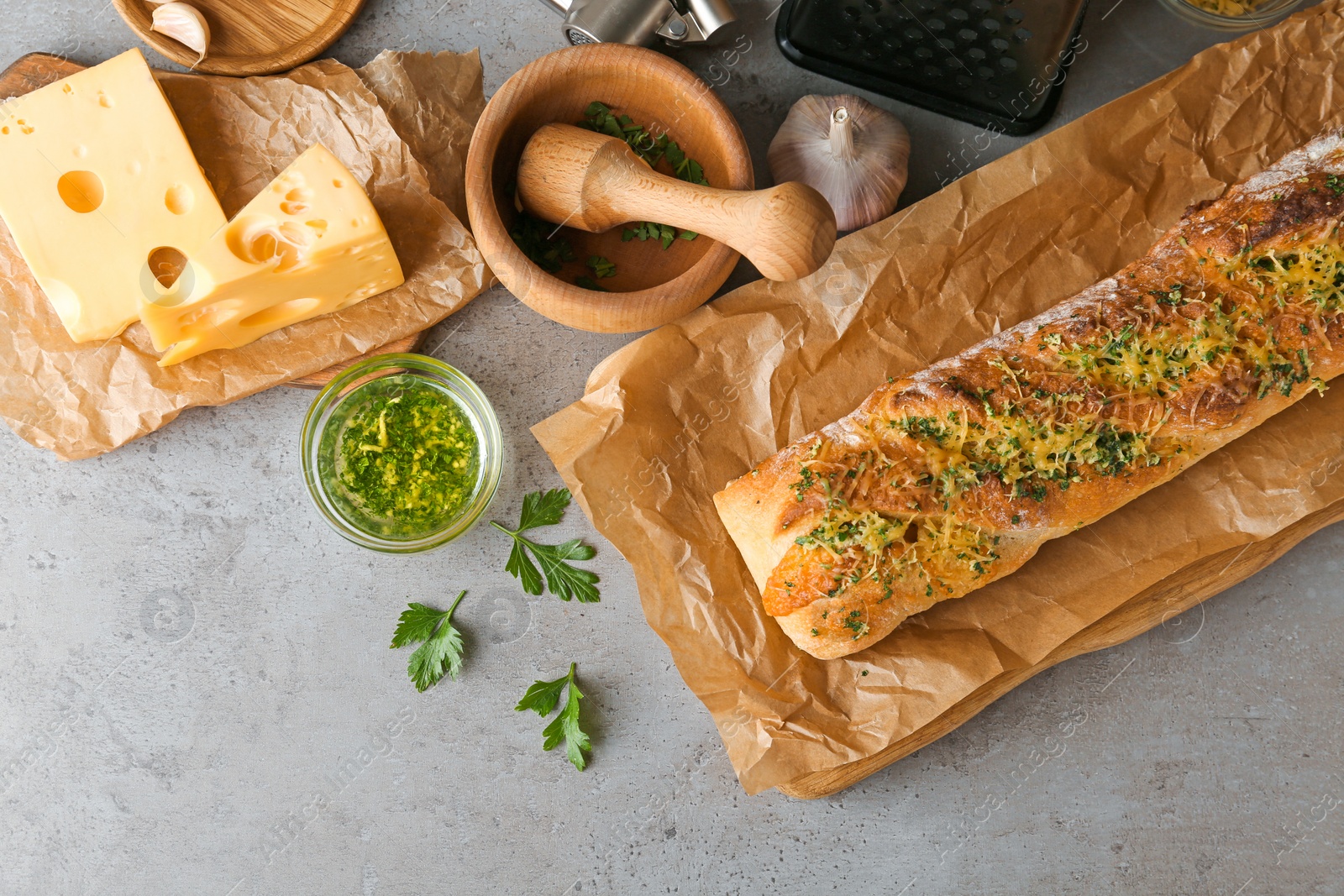 Photo of Tasty homemade garlic bread with cheese and herbs on grey table, flat lay