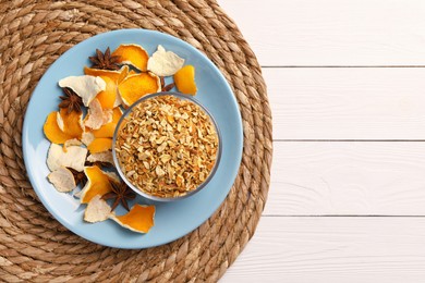 Bowl of dried orange zest seasoning, fresh peel and anise on white wooden table, top view. Space for text