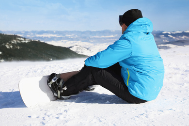 Photo of Man with snowboard on hill. Winter vacation