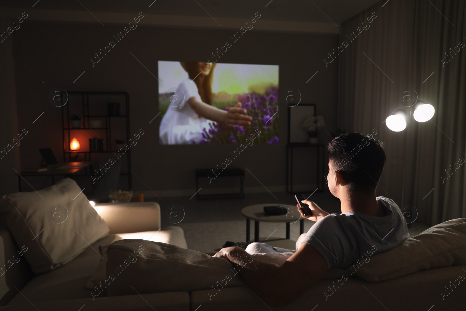 Photo of Man watching movie on sofa at night, back view. Space for text