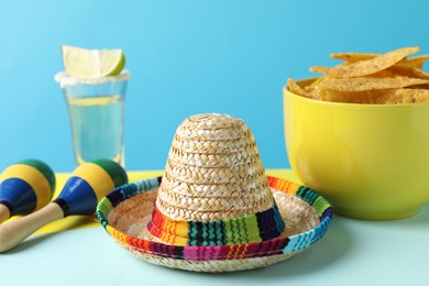 Mexican sombrero hat, nachos chips, maracas and tequila on color background