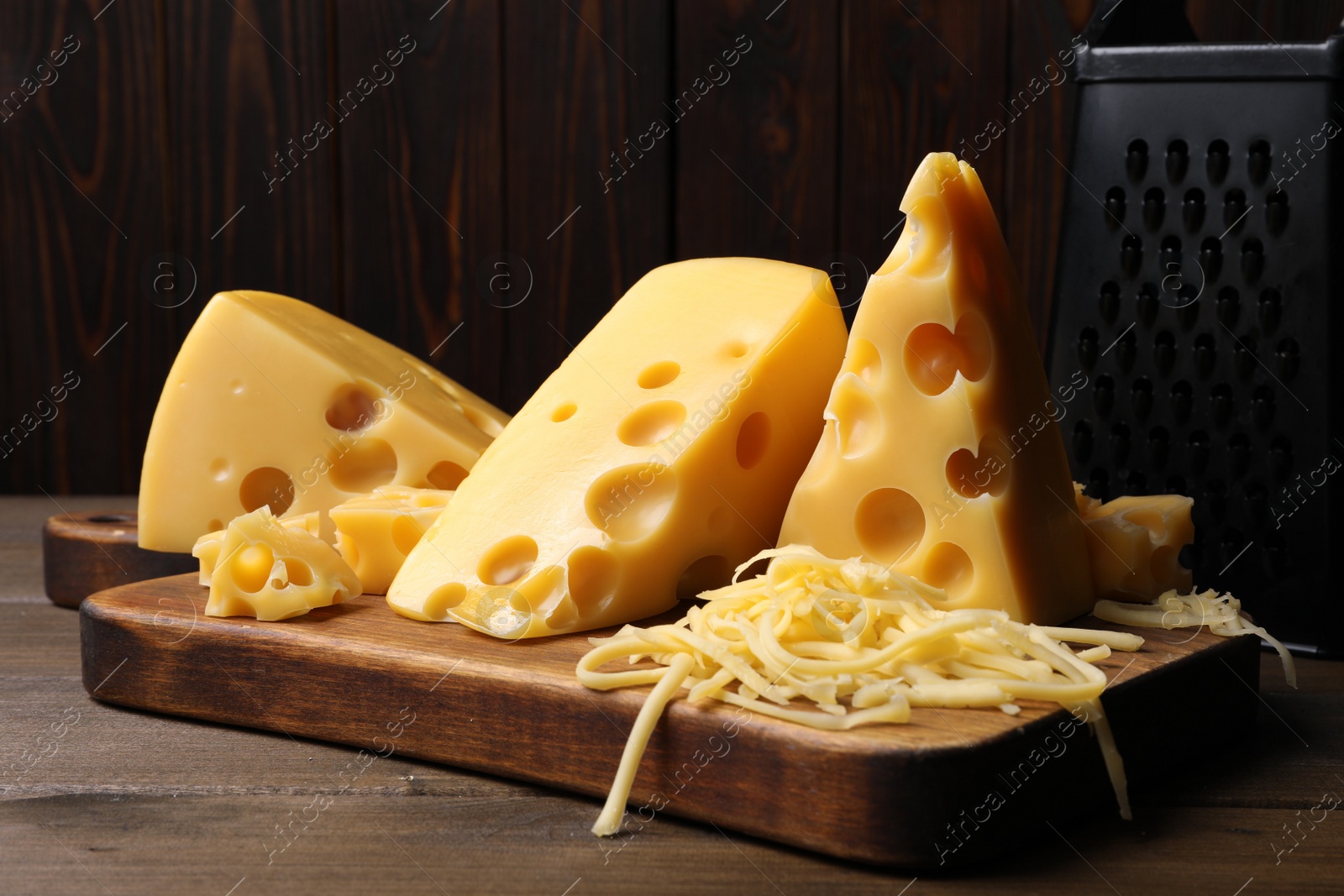 Photo of Tasty fresh cheese, grater and board on wooden table