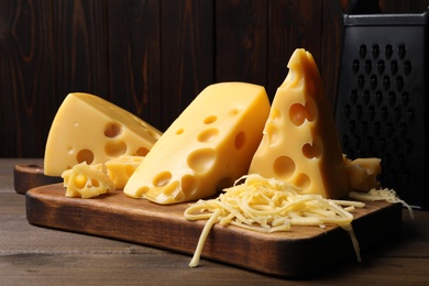 Photo of Tasty fresh cheese, grater and board on wooden table