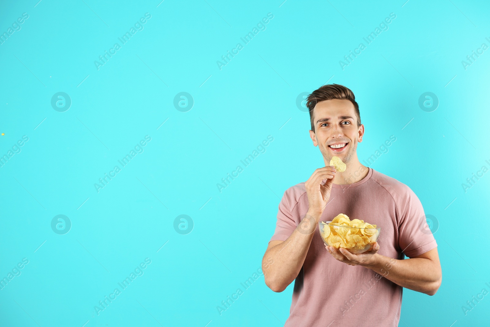 Photo of Man eating potato chips on color background. Space for text