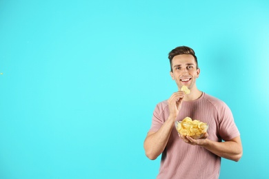 Photo of Man eating potato chips on color background. Space for text