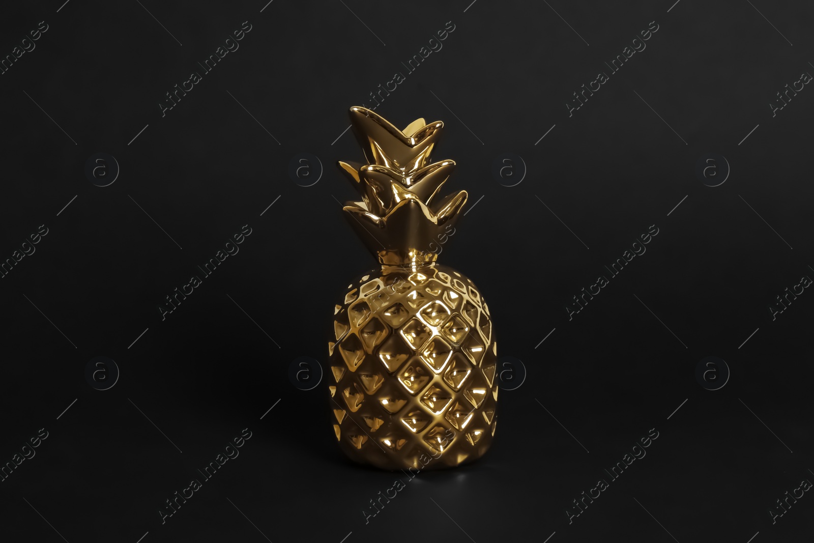 Photo of Gold metal decorative pineapple on black background