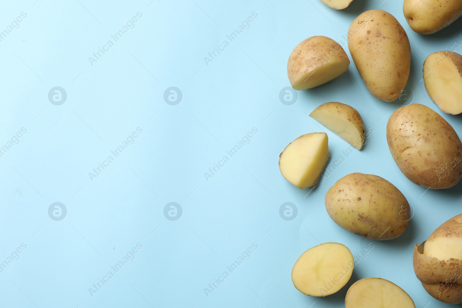 Photo of Fresh raw potatoes on light blue background, flat lay. Space for text