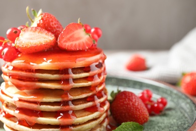 Delicious pancakes with fresh berries and syrup on table, closeup