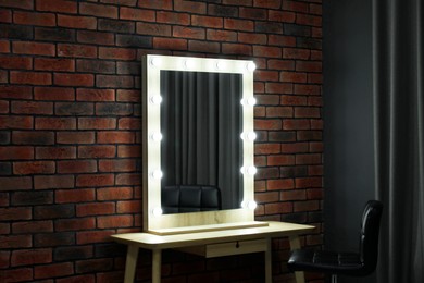 Photo of Mirror with light bulbs, table and chair in makeup room