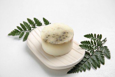 Photo of Soap bar with dish and green leaves on white background. Eco friendly personal care product
