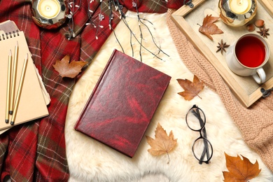 Photo of Flat lay composition with book, cup of tea and warm blanket on fuzzy rug