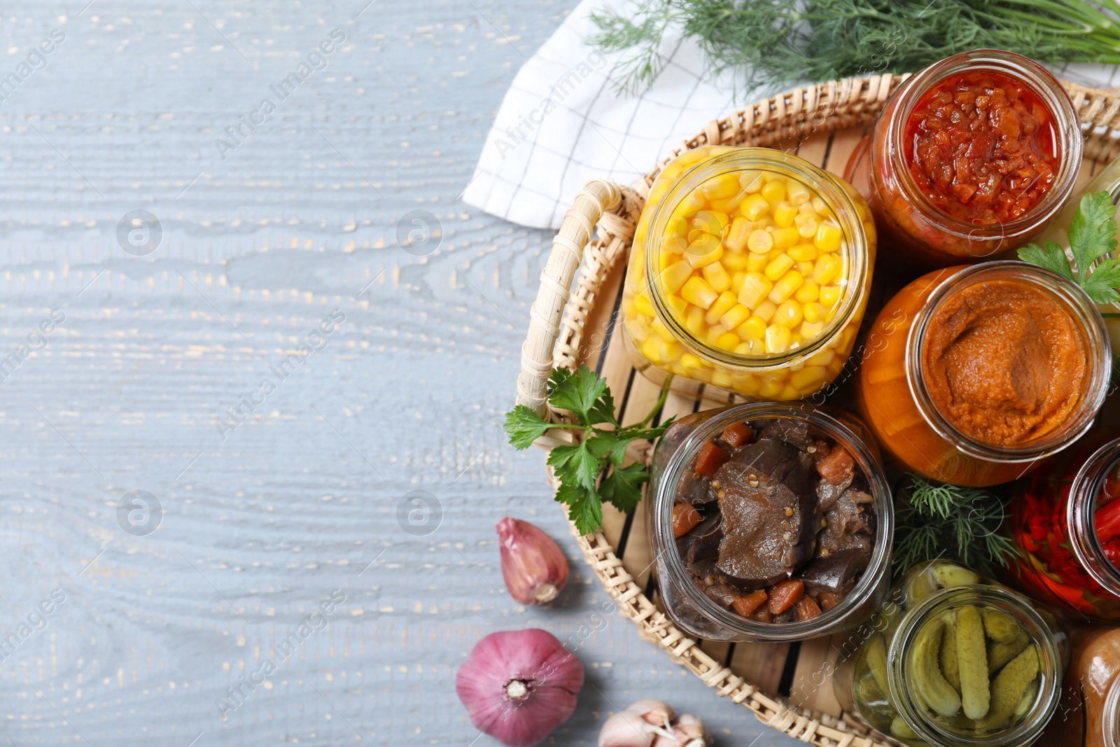 Photo of Tray with jars of pickled vegetables on light wooden table, flat lay. Space for text