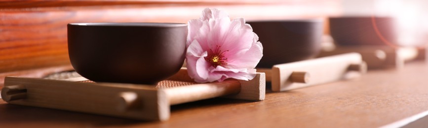 Image of Cup with sakura flower for traditional tea ceremony on wooden table. Banner design