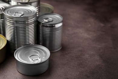 Photo of Many closed tin cans on brown table. Space for text