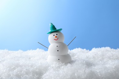Photo of Funny snowman on snow against light blue background