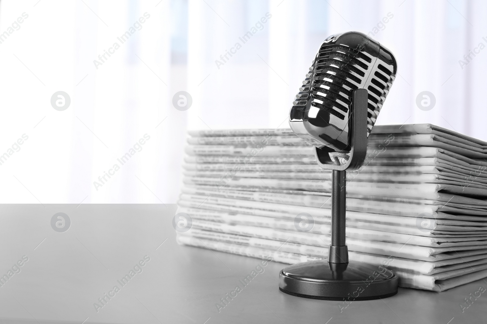 Photo of Newspapers and vintage microphone on grey table, space for text. Journalist's work