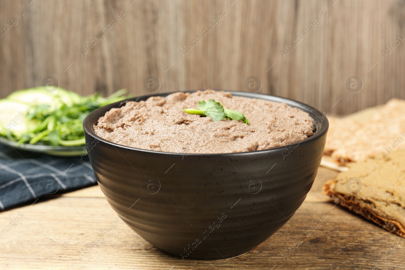 Photo of Tasty liver pate with herb in bowl on wooden table