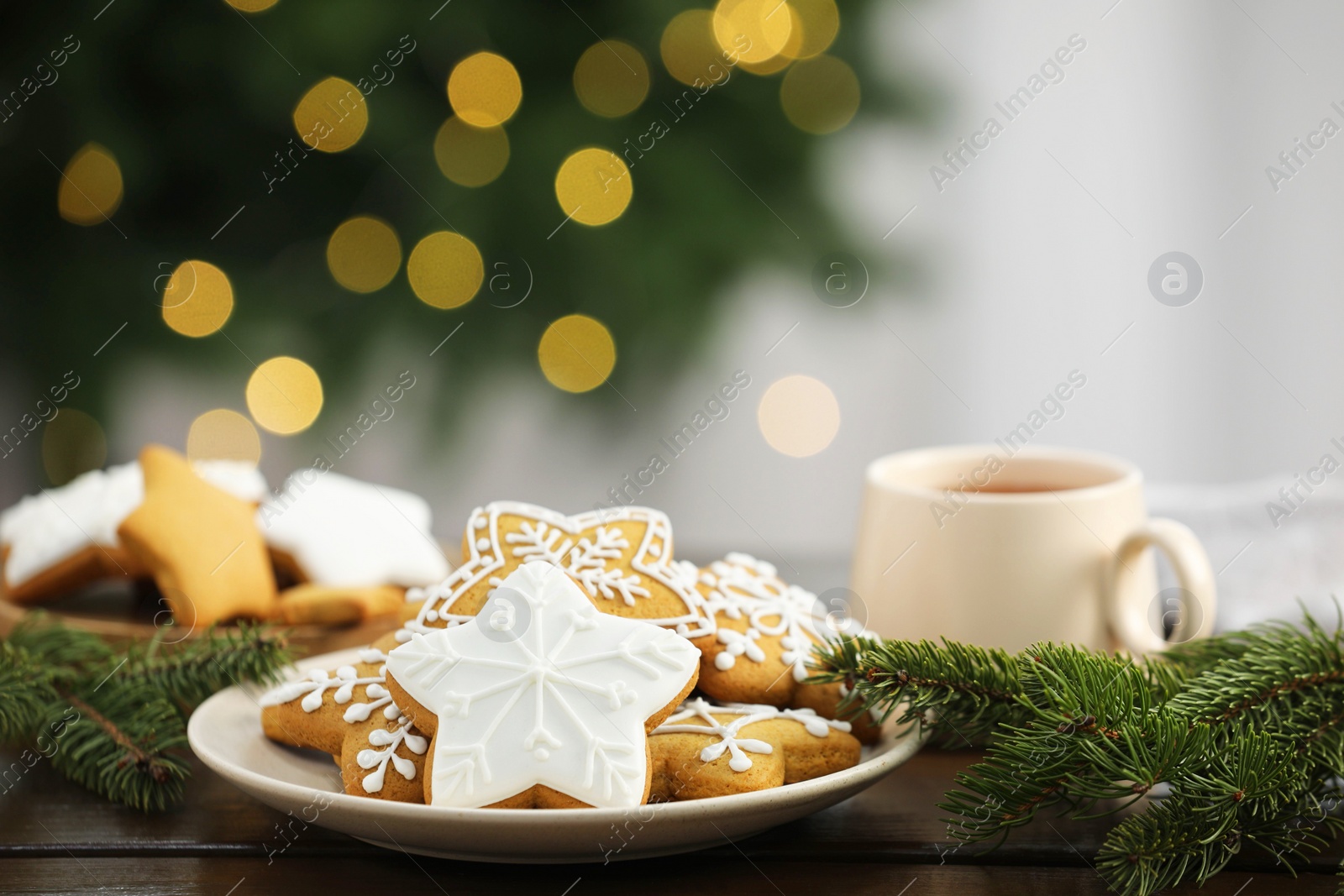 Photo of Decorated cookies and hot drink on wooden against blurred Christmas lights