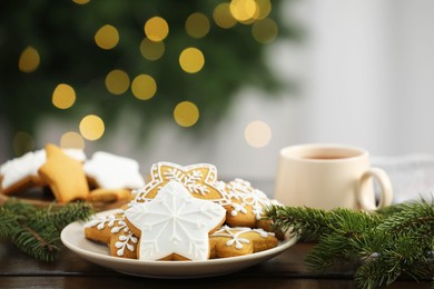 Decorated cookies and hot drink on wooden against blurred Christmas lights