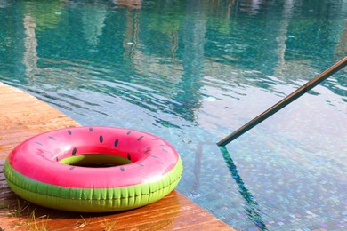 Photo of Inflatable ring on wooden deck near swimming pool. Luxury resort