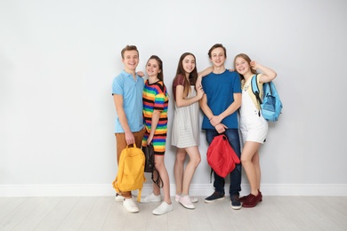 Group of teenagers against light wall. Youth lifestyle and friendship