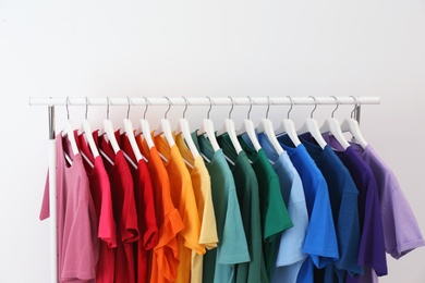 Photo of Rack with bright clothes on white background. Rainbow colors