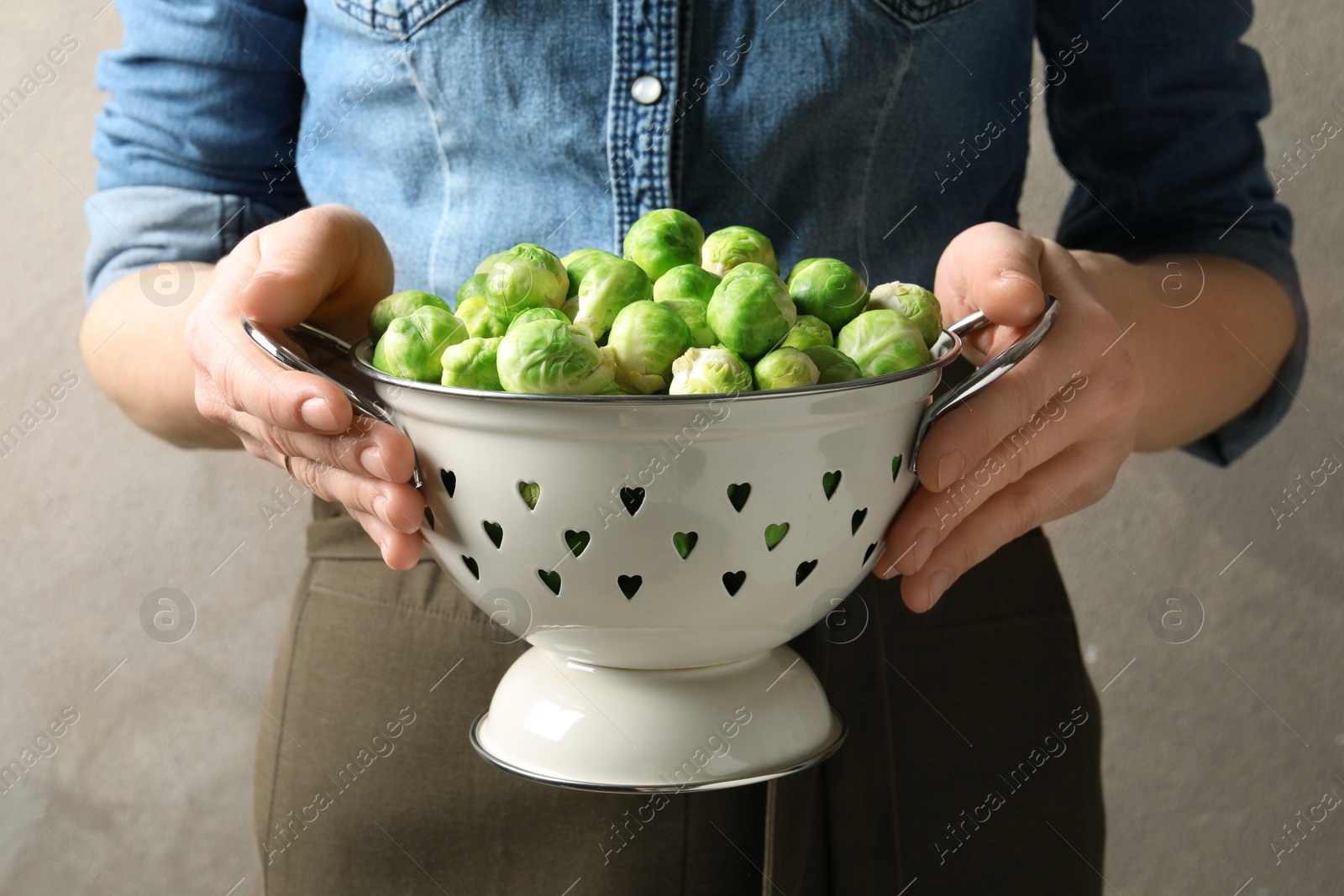 Photo of Woman holding colander with fresh Brussels sprouts, closeup