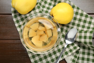 Photo of Delicious quince drink in glass bowl, fresh fruits and spoon on wooden table, top view