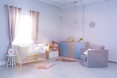 Photo of Baby room interior with comfortable crib and armchair